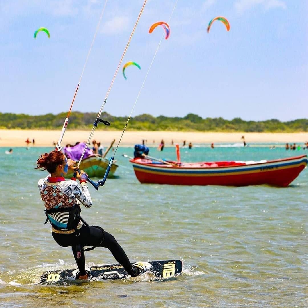 Uma pessoa praticando kitesurf, um esporte aquático radical que combina elementos de surfe, windsurf e wakeboard.